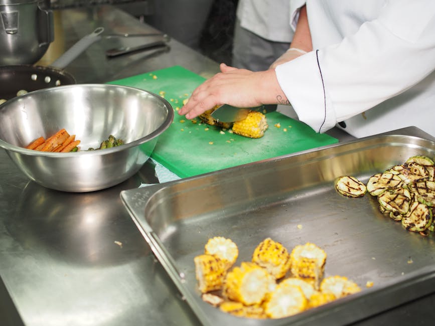 Chef slicing grilled corn and zucchini in a professional kitchen setting