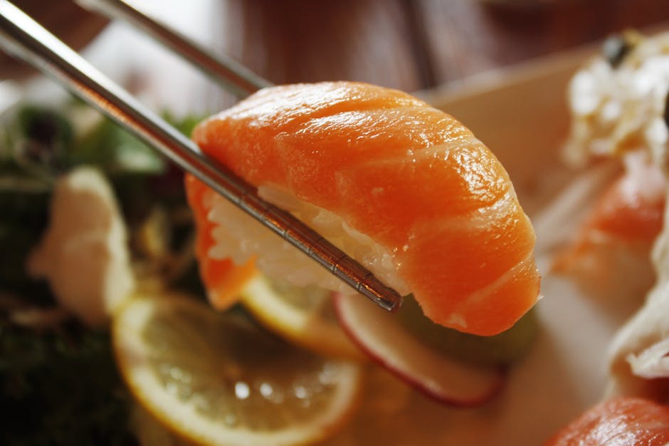 Mouthwatering salmon nigiri sushi held by chopsticks, ready to eat